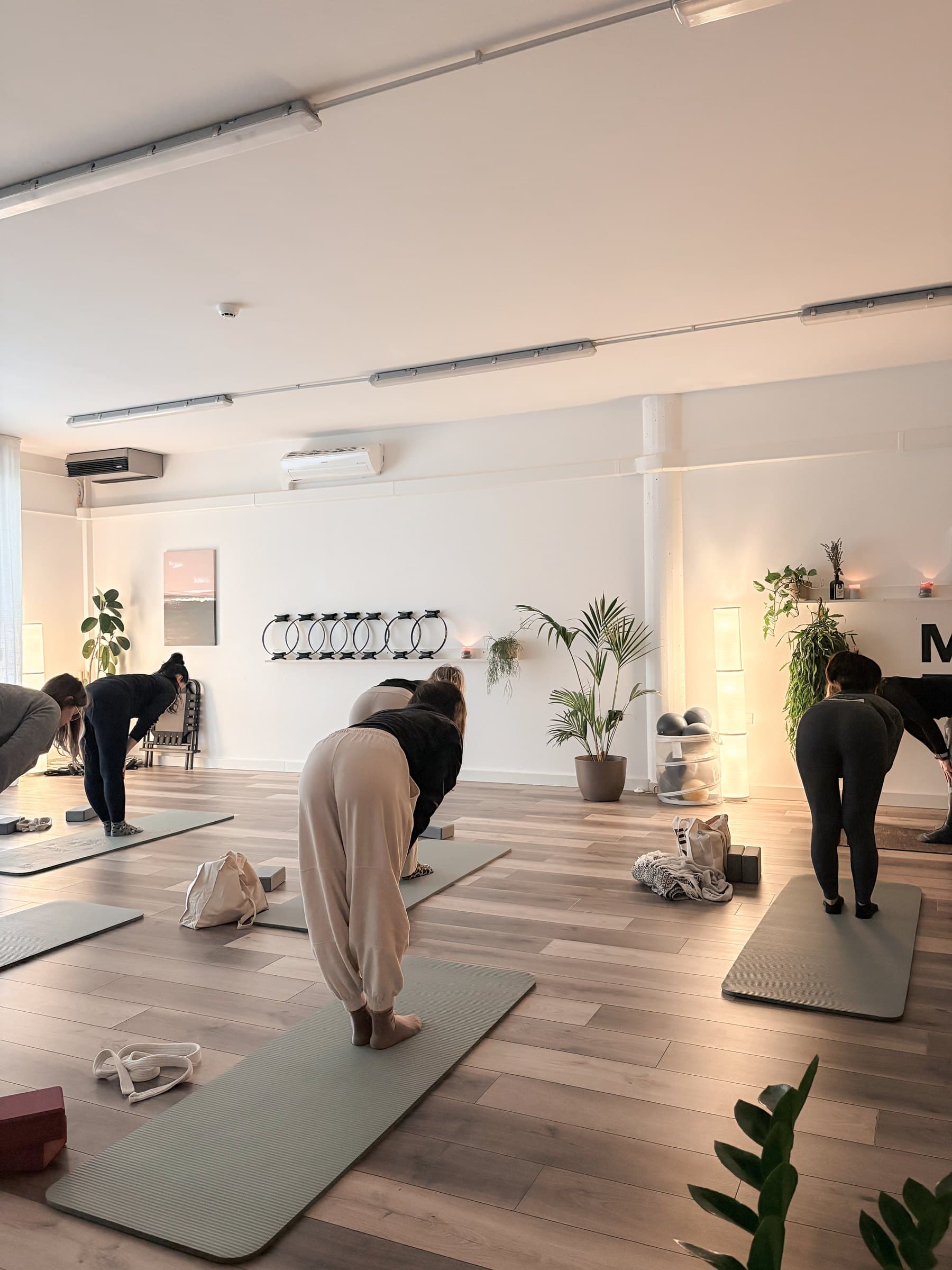 Lezione di yoga in gruppo nella sala grande, in piegamento in avanti sui tappetini